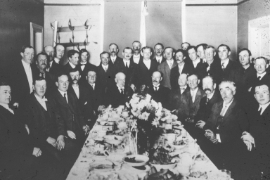 Men posed around a dining table