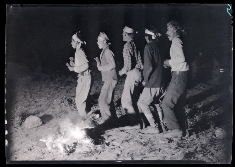 Navajo men dance in a line around a campfire